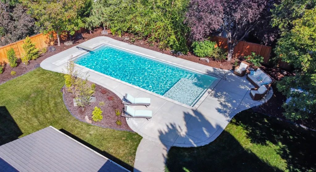 Aerial view of a pool with a curved concrete deck and planting