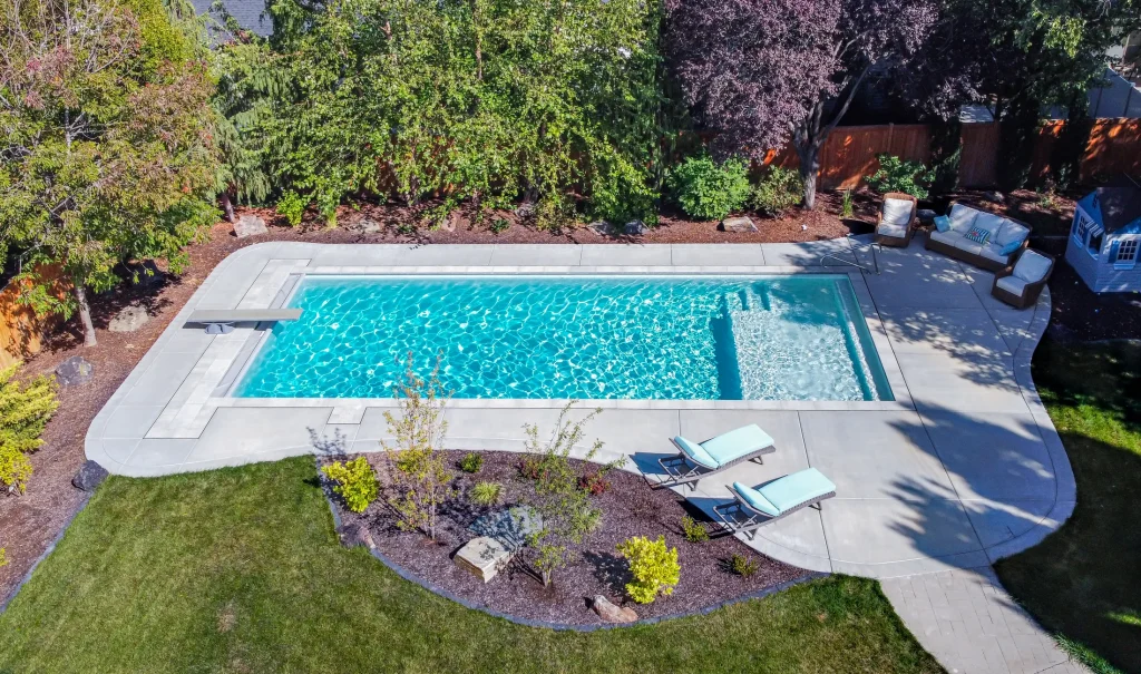 Aerial view of a pool with a curved concrete deck and planting