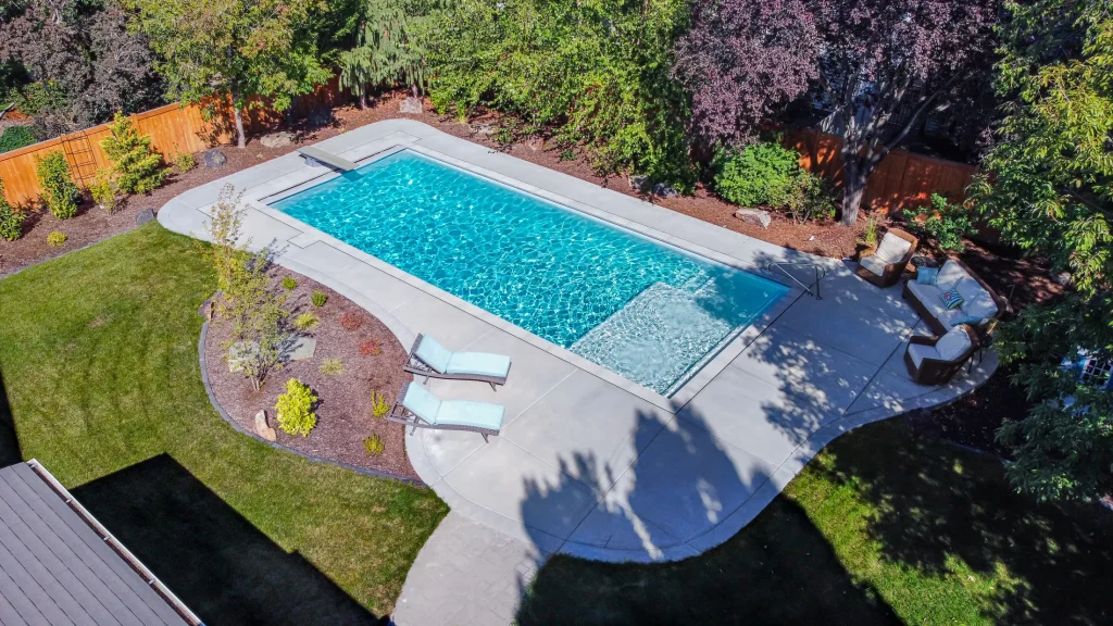 Aerial view of a pool with a curved concrete deck and planting