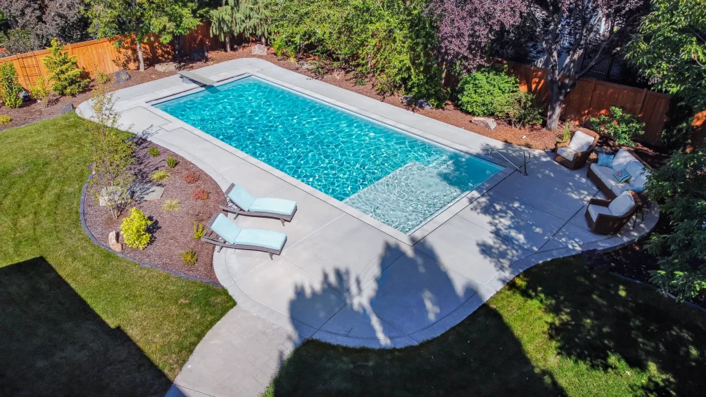 Aerial view of a pool with a curved concrete deck and planting