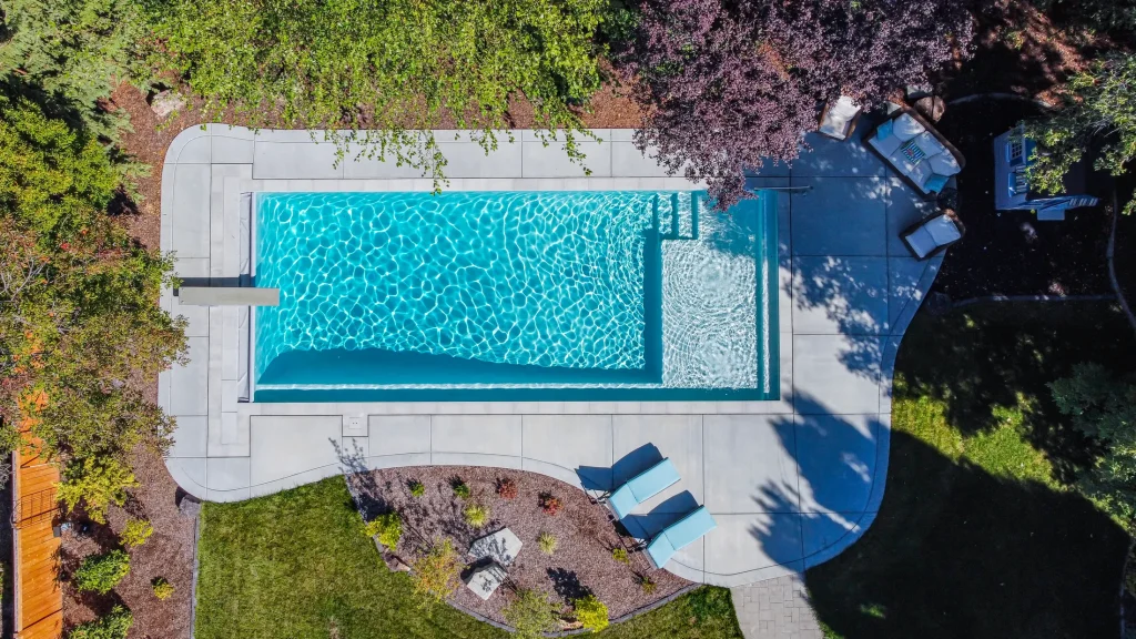 Aerial view of a pool with a curved concrete deck and planting