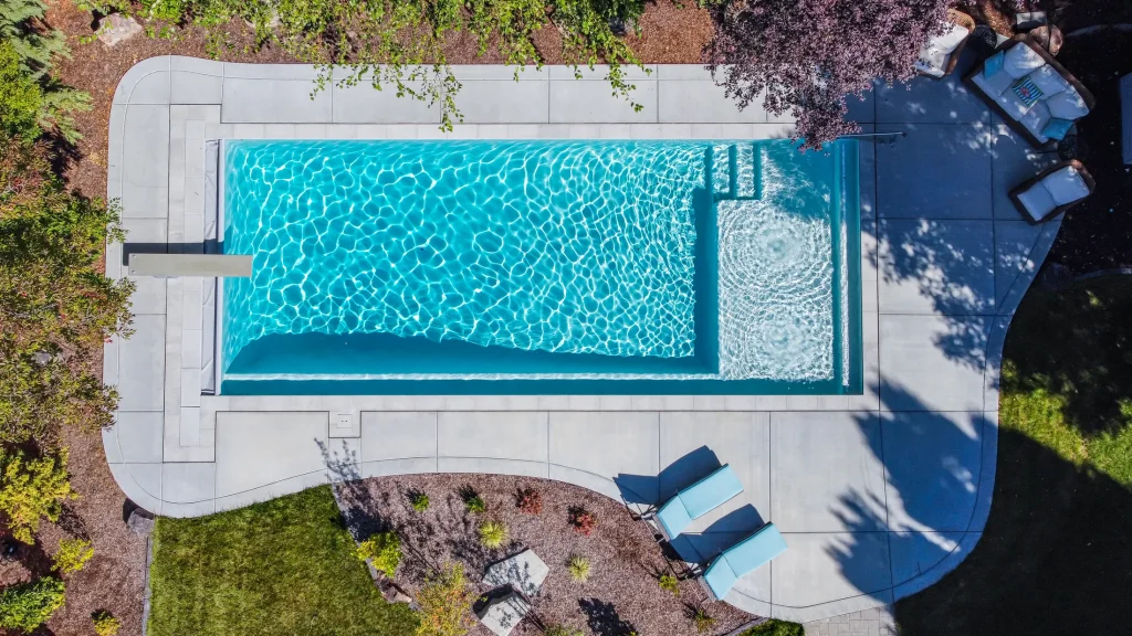 Aerial view of a pool with a curved concrete deck and planting