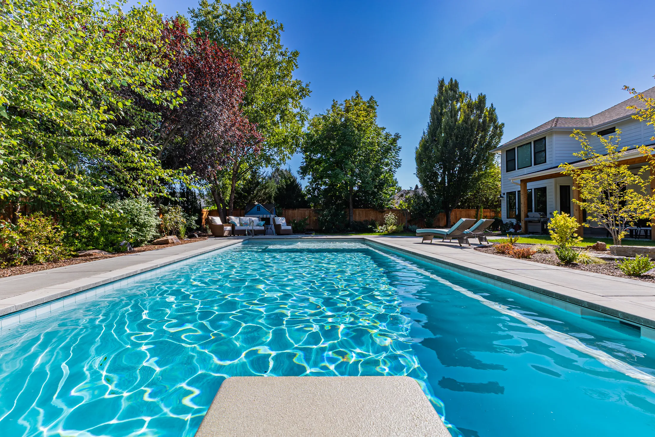 Pool with a wide concrete deck and mature trees